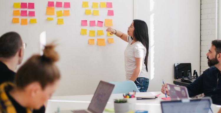 Woman pointing to a vision board in a meeting.